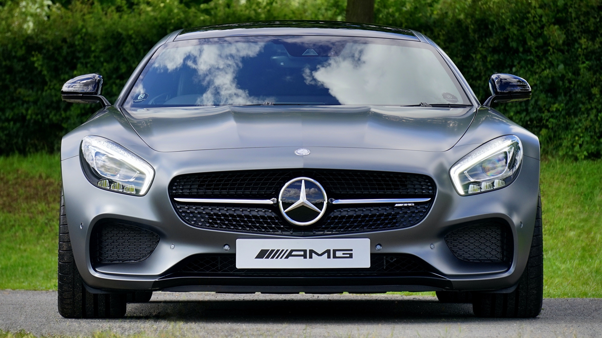 Front view of a Mercedes-AMG sports car with a matte grey finish parked outdoors.